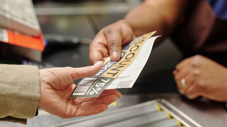 Cashier passing a coupon to a shopper