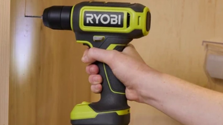 Person drilling hole in paneling with Ryobi 12V drill