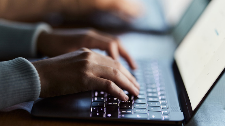 Person typing on laptop keyboard
