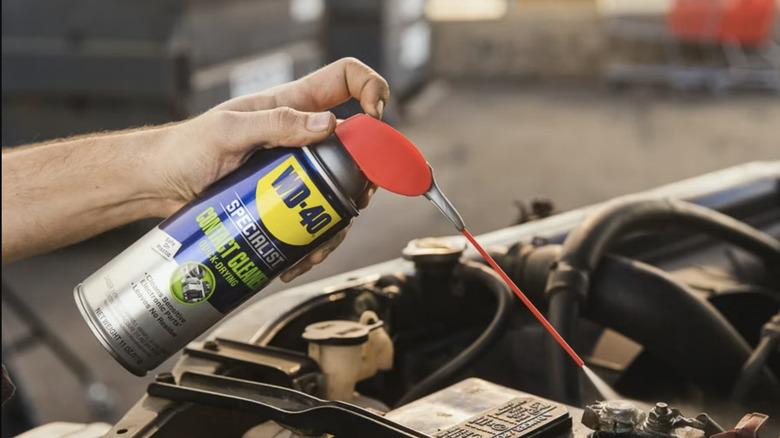 Mechanic spraying WD-40 in car