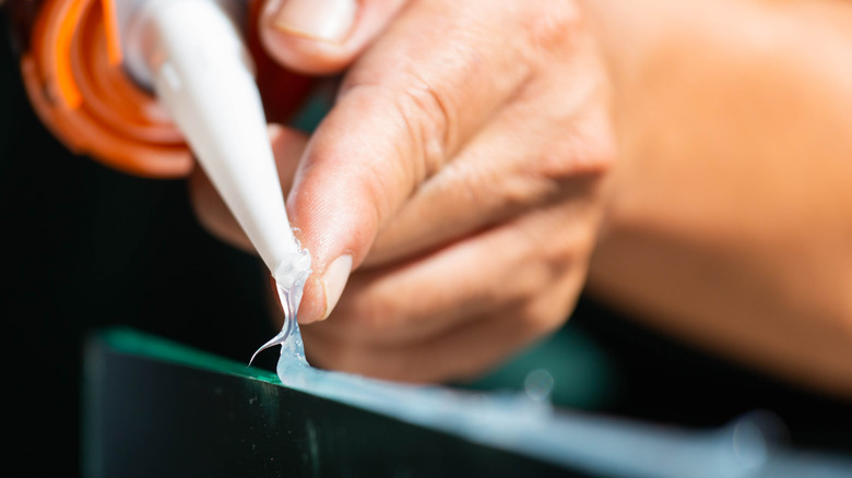 Close-up of a hand applying silicone sealant to a surface