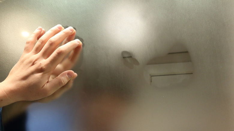 Hand on a fogged bathroom mirror