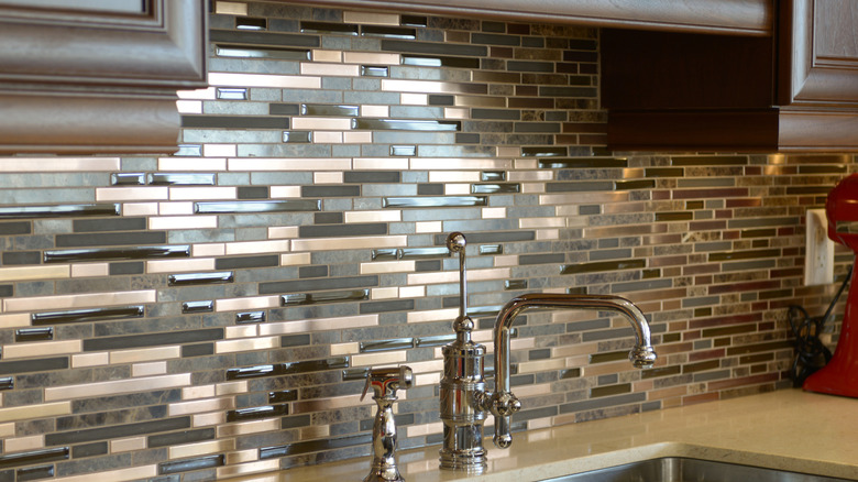 a kitchen with brown glass tiled backsplash