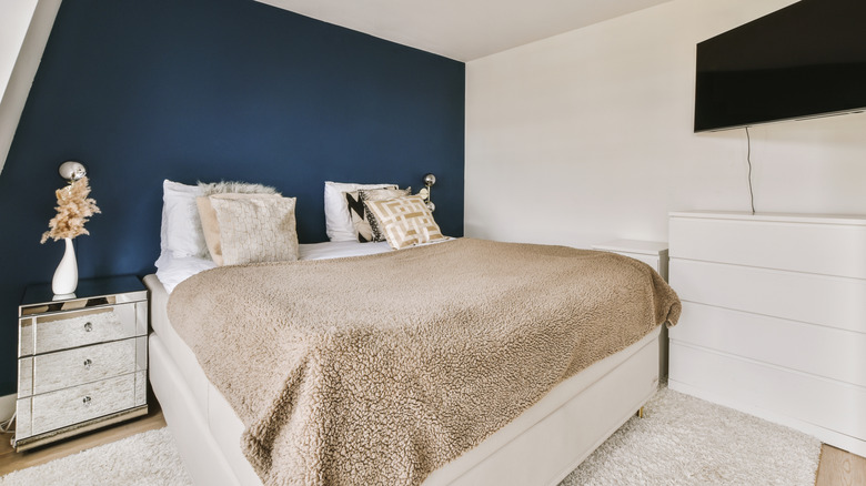 A bedroom with a blue accent wall.