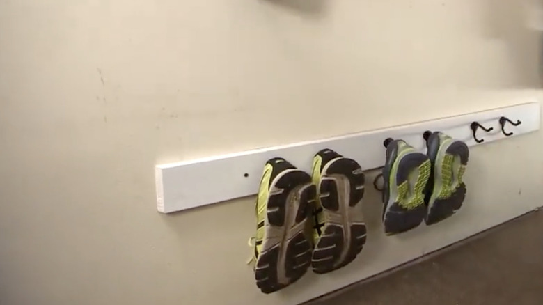 Coat hooks in a garage with shoes on them