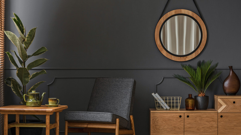 Gray chair between wooden table and console, against gray wall