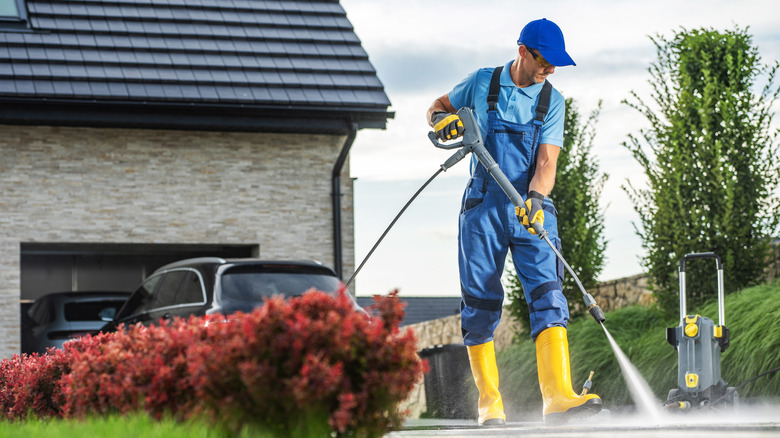 man with pressure washer cleaning a driveway