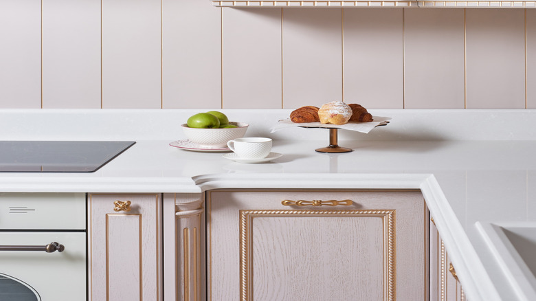kitchen with light pink cabinets and matching wood paneled backsplash