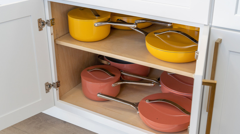 Pink and yellow pots stored with their lids in a cabinet