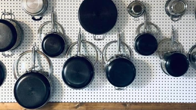 Pots hung with their lids on a pegboard