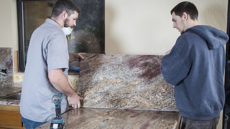 Two workers installing a granite countertop