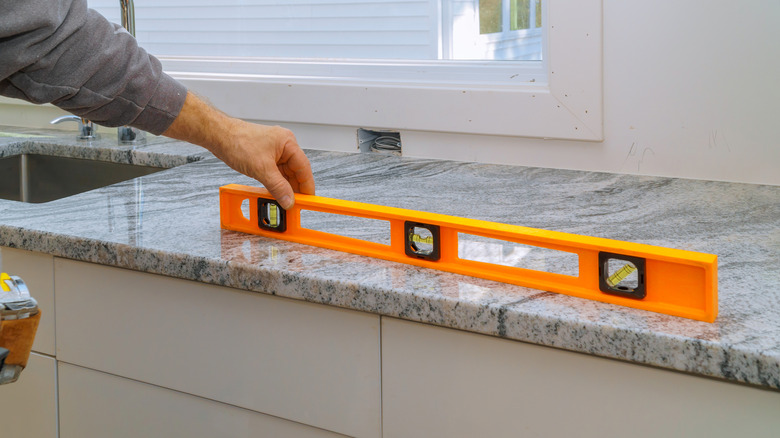 construction worker holding a spirit level on newly installed granite countertop