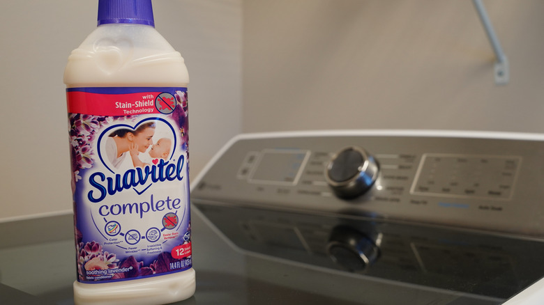 A bottle of Suavitel laundry detergent on a washing machine.