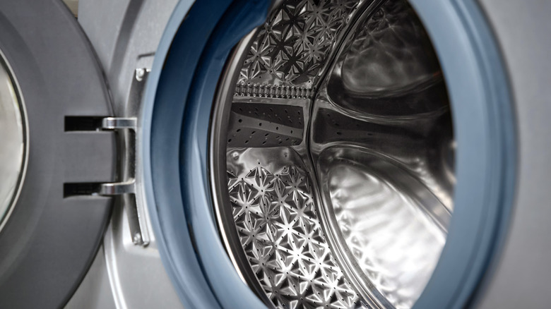 The door of a front-loading washing machine is open to reveal a sparkling interior