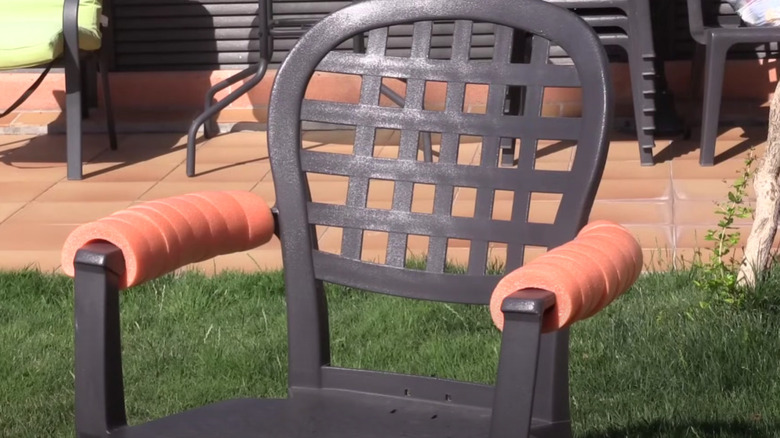 A patio chair with pool noodles wrapped around the arms.