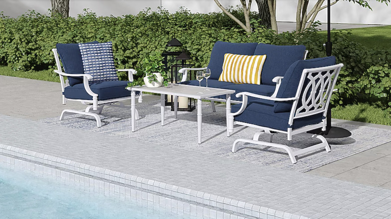 Elegant patio furniture set with blue cushions near a pool