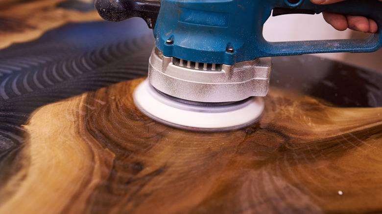Hands polishing epoxy countertop with sander