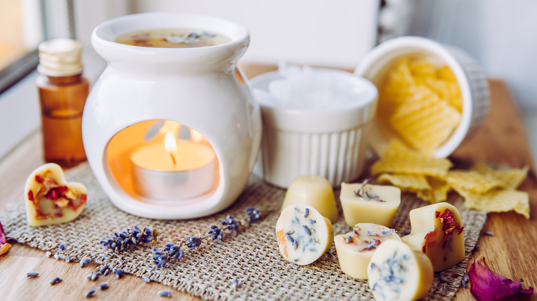 A white ceramic fragrance warmer is surrounded by aromatics