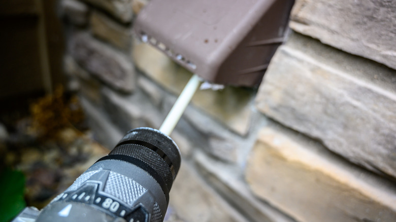 a drill connected to a brush cleans a dryer vent