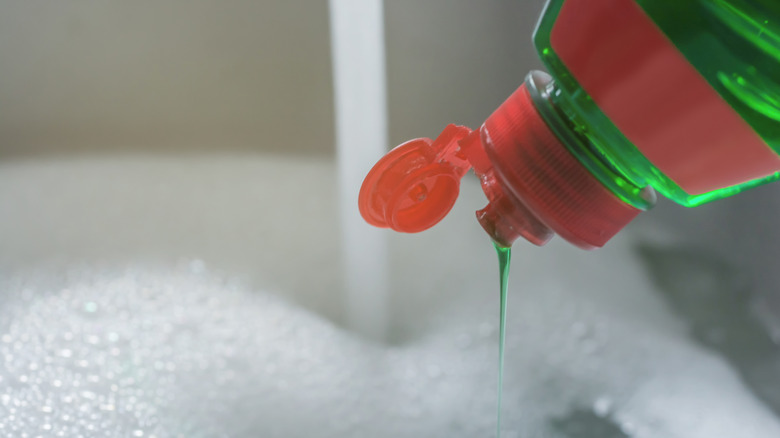 Green dish soap being added to running water