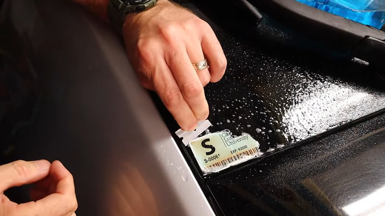 Removing a window decal with a razor blade and glass cleaner