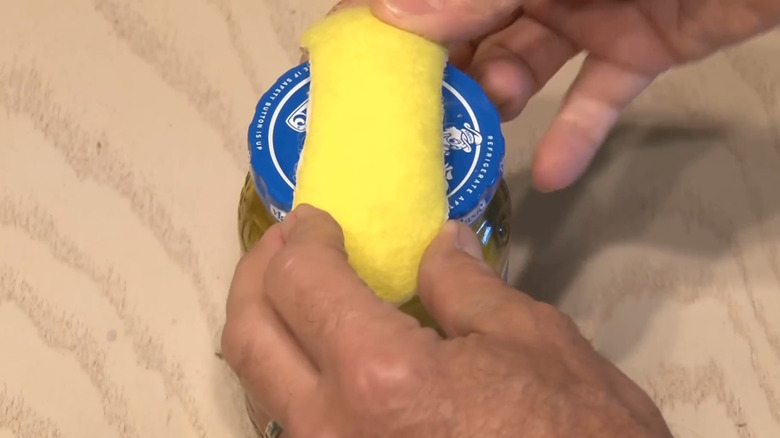A tennis ball cut along its visible seam and used to open a jar