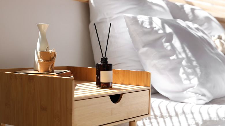 Reed diffuser sitting on nightstand next to bed