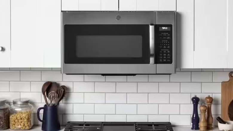 A stainless steel GE over-the-range microwave is surrounded by white cabinets