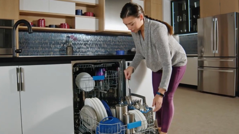 A woman pulls silverware out of a GE Profile smart dishwasher