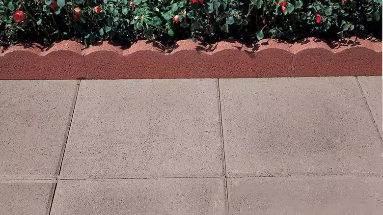 Pewter concrete step stones are installed next to a scalloped flowerbed border