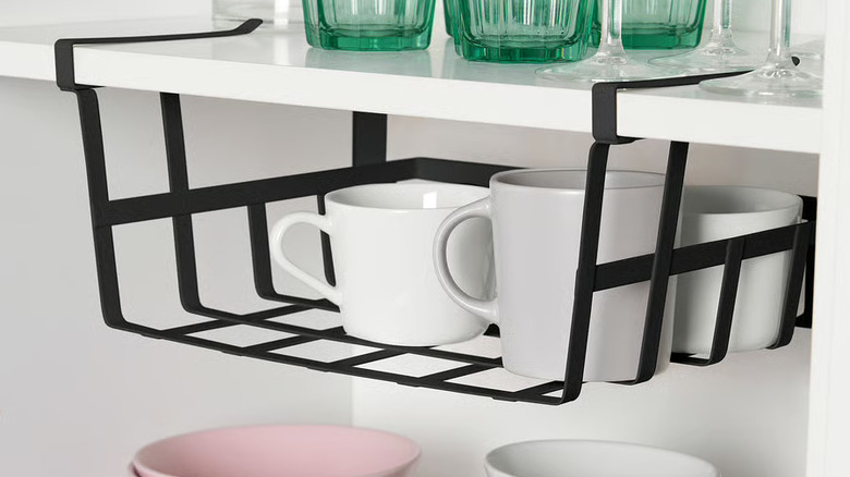 IKEA PÅLYCKE clip on storage basket on the under side of a cabinet shelf holding mugs