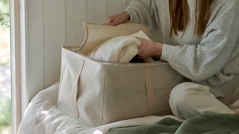 woman putting a folded sweater into the IKEA PURRPINGLA storage case