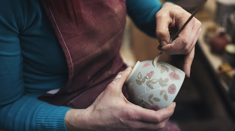 Person painting teacup
