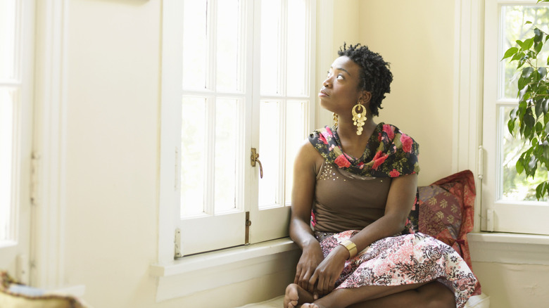A woman looks up at a blank yellow wall in her house, thinking