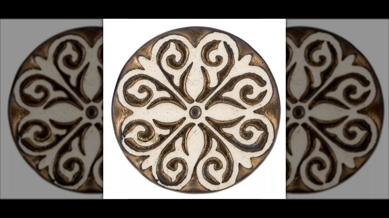Brown and cream doorknob with a floral scroll pattern