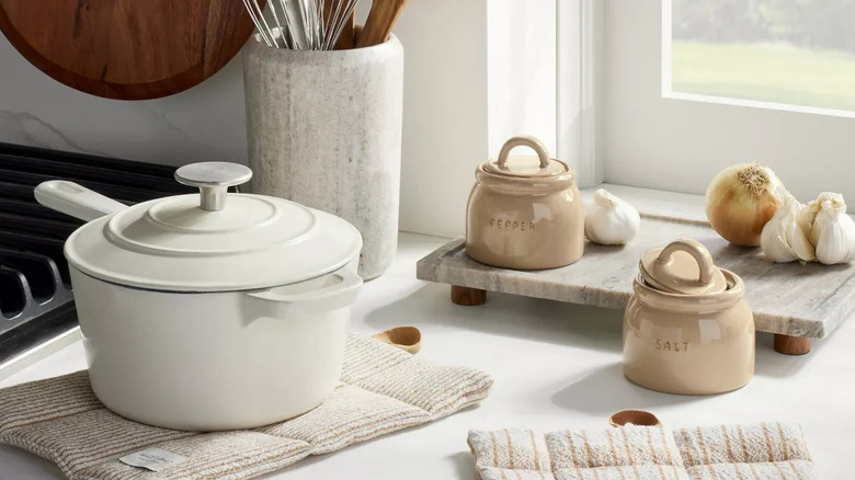 An onion, heads of garlic, and a spice jar sit on top of a footed marble tray surrounded by kitchen essentials