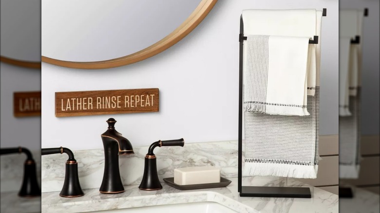 A matte black metal hand towel stand sits next to a bathroom sink