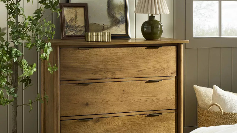 Decorative items sit on top of a three drawer wooden dresser