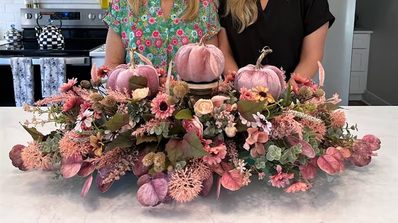 Two people stand behind a large pink fall-themed centerpiece