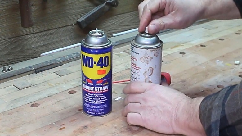 person taking spray paint nozzle off can to put on WD-40 can