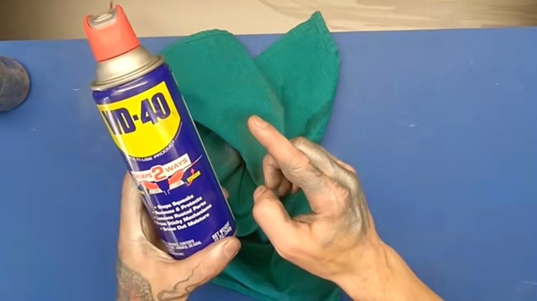 person with grease-covered hands holding can of WD-40