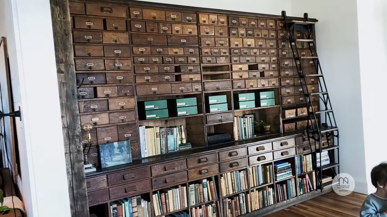 A large antique bookcase with rolling ladder is shown in Joanna Gaines' home
