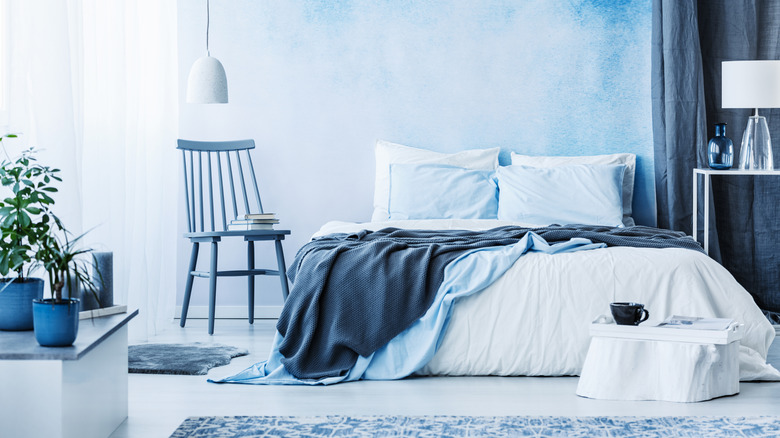 A bed and chair sit in front of a blue ombre wall
