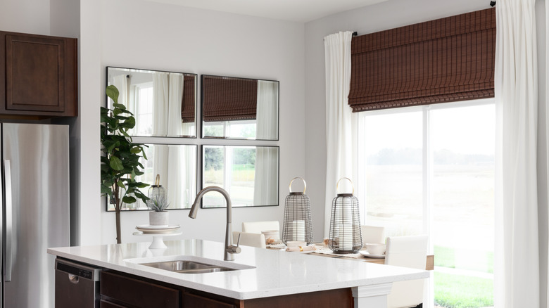 A kitchen and dining space with a large sliding glass door and different blind and curtain types.