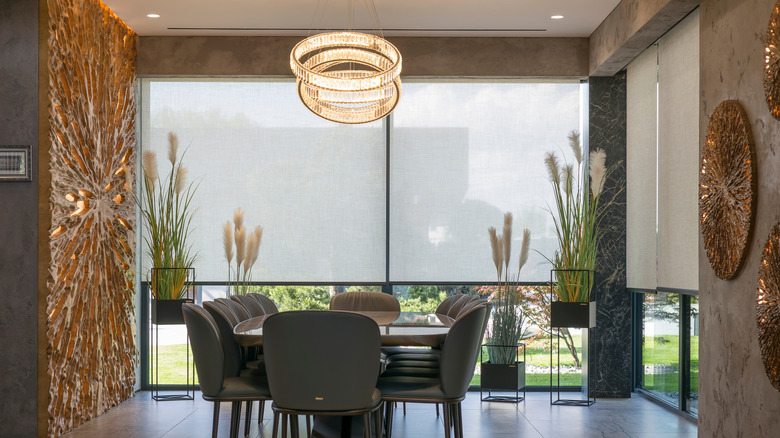 An opulent dining room with heavy roller blinds covering windows and a sliding glass door.