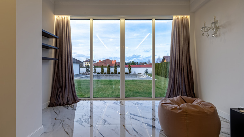 A set of sliding glass doors with curtains and uplighting at the top.