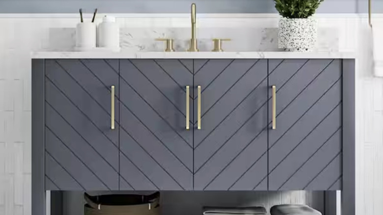 Ash blue bath vanity with a single sink and gold handles