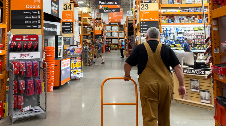 Person walking through the aisles at Home Depot with a flatbed cart