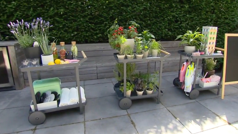 A variety of entertaining and gardening items are arranged on three simple bar carts.