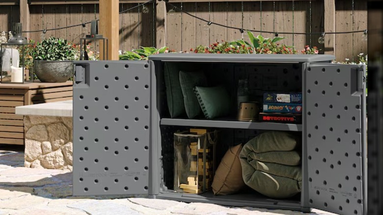 Throw pillows and other items are stored in a gray Suncast outdoor storage cabinet.